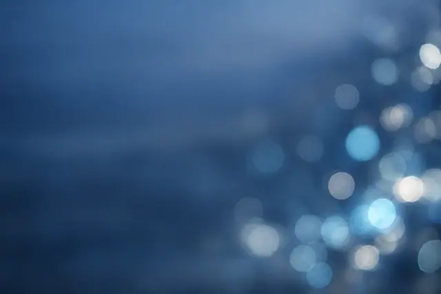 Luzes bokeh azuis e prateadas à direita sobre fundo azul suave, com amplo espaço livre à esquerda.