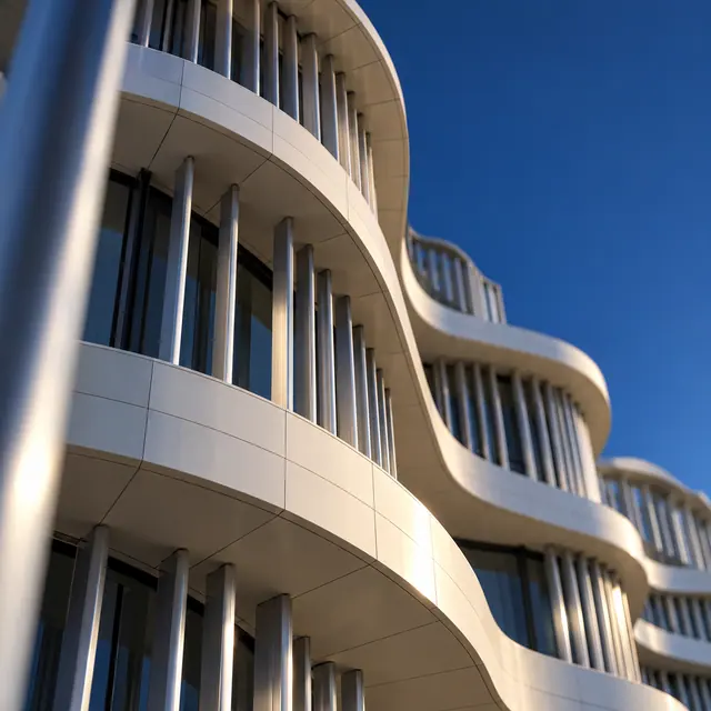 Fachada moderna com curvas claras e linhas metálicas verticais, iluminada pelo sol sob um céu azul.
