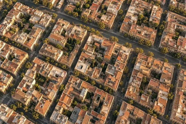 Vista aérea de quadras com telhados de terracota e pátios arborizados sob a luz dourada do fim da tarde.