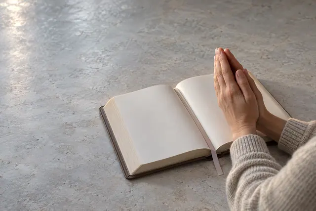 Mãos unidas em oração sobre uma Bíblia aberta de páginas sem inscrições, com luz suave e tons neutros.