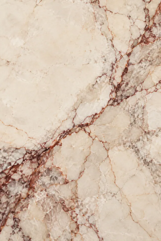 Textura de mármore marfim com veios em ferrugem e vinho na diagonal e nuances acinzentadas.