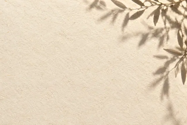 Papel marfim com fibras delicadas e sombras suaves de folhas no alto e à direita, com amplo espaço livre à esquerda.