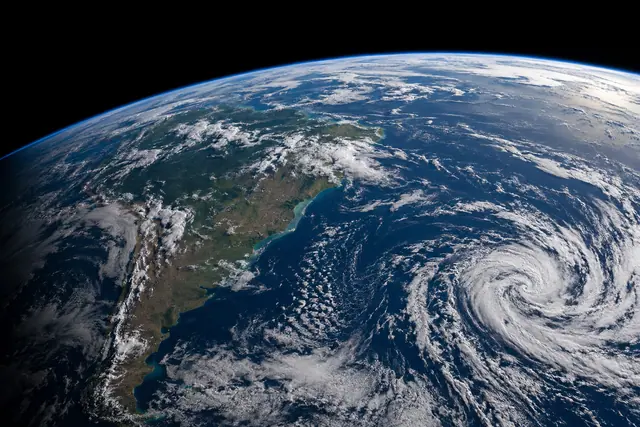 Terra vista do espaço, com América do Sul, nuvens em espiral no Atlântico e uma fina borda azul na atmosfera.